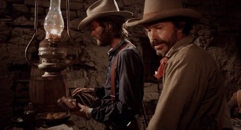 Movie still from “The Hired Hand” (1971), directed by Peter Fonda – A couple of men standing next to each other in a room; Medium shot, Over the shoulder angle