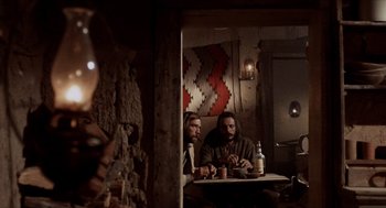 Movie still from “The Hired Hand” (1971), directed by Peter Fonda – Two men sitting at a table in front of a painting; Medium shot, Low angle