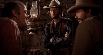 Movie still from “The Hired Hand” (1971), directed by Peter Fonda – A man in a cowboy hat standing next to another man; Medium shot, Over the shoulder angle