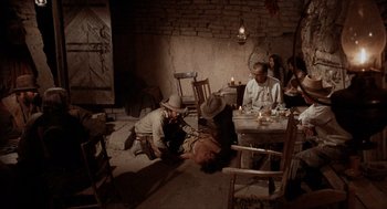 Movie still from “The Hired Hand” (1971), directed by Peter Fonda – A group of people sitting around a table; Wide shot, High angle