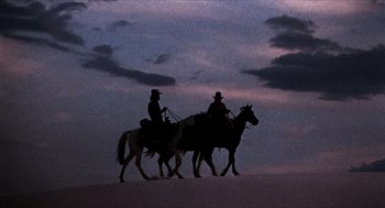 Movie still from “The Hired Hand” (1971), directed by Peter Fonda – Two people riding horses in the desert at night; Wide shot, Low angle