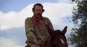 Movie still from “The Hired Hand” (1971), directed by Peter Fonda – A man sitting on top of a brown horse; Close Up shot, Low angle
