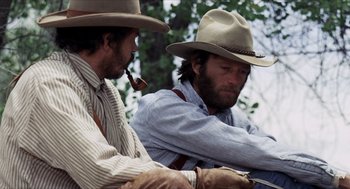 Movie still from “The Hired Hand” (1971), directed by Peter Fonda – A couple of men sitting next to each other on top of a hill; Medium shot, Low angle