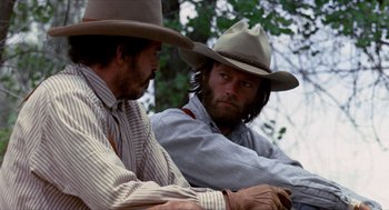 Movie still from “The Hired Hand” (1971), directed by Peter Fonda – Two men in cowboy hats talking to each other; Medium shot, Over the shoulder angle