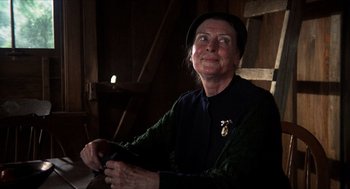 Movie still from “The Hired Hand” (1971), directed by Peter Fonda – An older woman wearing a hat and holding a knife; Close Up shot, Over the shoulder angle