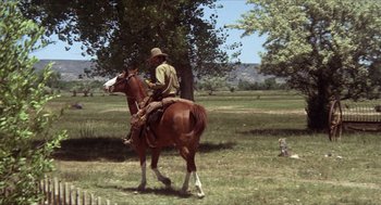 Movie still from “The Hired Hand” (1971), directed by Peter Fonda – A man riding on the back of a brown horse; Wide shot, Low angle