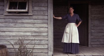 Movie still from “The Hired Hand” (1971), directed by Peter Fonda – A woman standing in front of a wooden building; Wide shot, Low angle