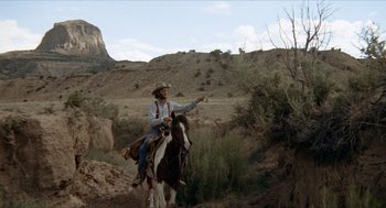 Movie still from “The Hired Hand” (1971), directed by Peter Fonda – A man riding a horse in the middle of a field; Wide shot, Low angle
