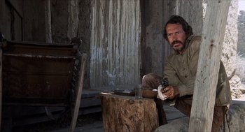 Movie still from “The Hired Hand” (1971), directed by Peter Fonda – A man sitting on the ground holding a gun; Medium shot, Low angle