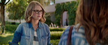 Movie still from “The House” (2017), directed by Andrew Jay Cohen – A woman wearing a jean jacket and glasses looking at a man; Close Up shot, Over the shoulder angle