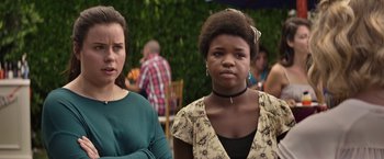 Movie still from “The House” (2017), directed by Andrew Jay Cohen – Two women standing next to each other in front of some people; Close Up shot, Over the shoulder angle