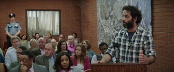Movie still from “The House” (2017), directed by Andrew Jay Cohen – A crowd of people sitting in a room; Medium shot, Over the shoulder angle