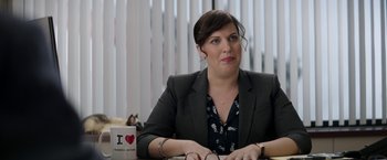 Movie still from “The House” (2017), directed by Andrew Jay Cohen – A woman sitting at a table in front of a laptop; Medium shot, Over the shoulder angle