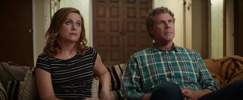 Movie still from “The House” (2017), directed by Andrew Jay Cohen – A man and a woman sitting next to each other on a couch; Medium shot, Over the shoulder angle
