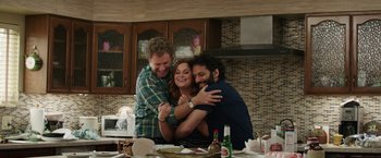 Movie still from “The House” (2017), directed by Andrew Jay Cohen – A group of three people hugging in a kitchen; Medium shot, High angle