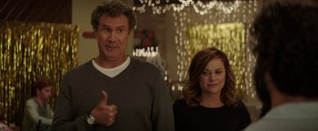 Movie still from “The House” (2017), directed by Andrew Jay Cohen – A man and a woman standing next to each other in front of lights; Medium shot, Over the shoulder angle