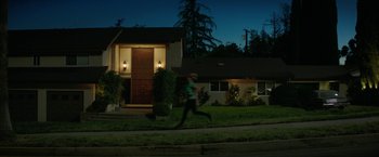 Movie still from “The House” (2017), directed by Andrew Jay Cohen – A woman running down the street in front of a house; Extreme Wide shot, Low angle