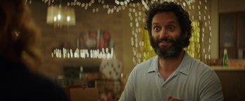 Movie still from “The House” (2017), directed by Andrew Jay Cohen – A man with a beard is smiling for the camera; Close Up shot, Over the shoulder angle