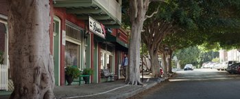 Movie still from “The House” (2017), directed by Andrew Jay Cohen – A man walking down the sidewalk in front of a store; Extreme Wide shot, High angle