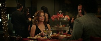 Movie still from “The House” (2017), directed by Andrew Jay Cohen – A woman sitting at a dinner table with a plate of lobster; Medium shot, Over the shoulder angle