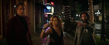 Movie still from “The House” (2017), directed by Andrew Jay Cohen – A beautiful woman holding a hair dryer on a city street at night; Medium shot, Over the shoulder angle