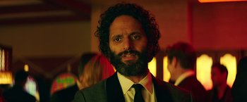 Movie still from “The House” (2017), directed by Andrew Jay Cohen – A man in a suit and tie with a beard; Close Up shot, Over the shoulder angle