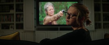 Movie still from “The House” (2017), directed by Andrew Jay Cohen – A woman sitting in front of a television; Close Up shot, Over the shoulder angle