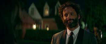Movie still from “The House” (2017), directed by Andrew Jay Cohen – A man in a suit and tie standing in front of a house; Close Up shot, Over the shoulder angle