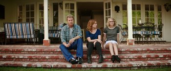 Movie still from “The House” (2017), directed by Andrew Jay Cohen – Three people sitting on the steps of a house; Wide shot, Over the shoulder angle