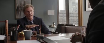 Movie still from “The House” (2017), directed by Andrew Jay Cohen – A man sitting at a table talking to another man; Medium shot, Over the shoulder angle