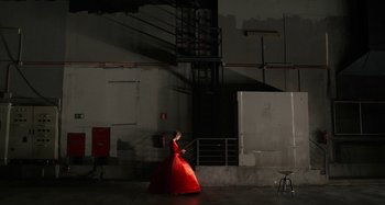 Movie still from “The Human Voice” (2020), directed by Pedro Almodóvar – A woman in a long red dress in an industrial setting; Wide shot, Low angle