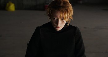 Movie still from “The Human Voice” (2020), directed by Pedro Almodóvar – A woman with red hair wearing a black shirt; Close Up shot, Low angle