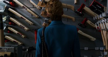 Movie still from “The Human Voice” (2020), directed by Pedro Almodóvar – A woman in a blue jacket is looking at a wall of hammers; Close Up shot, Over the shoulder angle