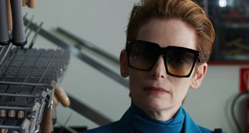 Movie still from “The Human Voice” (2020), directed by Pedro Almodóvar – A woman wearing sunglasses and a blue shirt; Close Up shot, Low angle