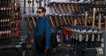 Movie still from “The Human Voice” (2020), directed by Pedro Almodóvar – A woman is holding a purse in a store; Medium shot, High angle