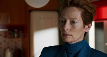 Movie still from “The Human Voice” (2020), directed by Pedro Almodóvar – An older woman wearing a blue jacket and a blue tie; Close Up shot, Over the shoulder angle