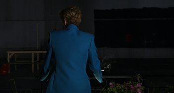 Movie still from “The Human Voice” (2020), directed by Pedro Almodóvar – A woman in a blue suit standing next to flowers; Medium shot, Over the shoulder angle