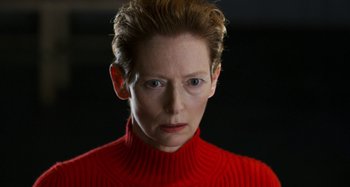 Movie still from “The Human Voice” (2020), directed by Pedro Almodóvar – Tilda swinton in a red sweater staring straight ahead; Close Up shot, Low angle