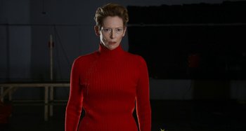 Movie still from “The Human Voice” (2020), directed by Pedro Almodóvar – A woman in a red sweater standing in a dark room; Medium shot, Low angle