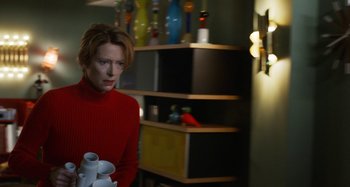 Movie still from “The Human Voice” (2020), directed by Pedro Almodóvar – A woman in a red sweater is holding some toilet paper; Medium shot, Over the shoulder angle