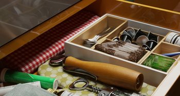 Movie still from “The Human Voice” (2020), directed by Pedro Almodóvar – A wooden box filled with silverware and other utensils on top of a table; Extreme Close Up shot, High angle