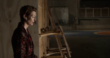 Movie still from “The Human Voice” (2020), directed by Pedro Almodóvar – A woman is standing in front of a wooden structure; Medium shot, Over the shoulder angle