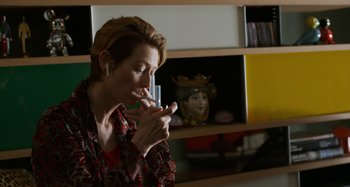 Movie still from “The Human Voice” (2020), directed by Pedro Almodóvar – A woman is drinking a glass of wine in a living room; Close Up shot, Over the shoulder angle