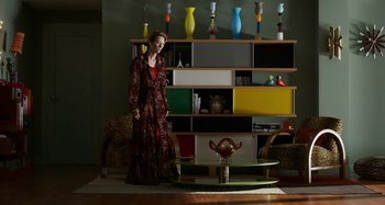 Movie still from “The Human Voice” (2020), directed by Pedro Almodóvar – A woman standing in front of a colorful bookcase in a living room; Wide shot, Low angle