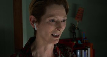 Movie still from “The Human Voice” (2020), directed by Pedro Almodóvar – An older woman wearing a red and black floral shirt; Close Up shot, Over the shoulder angle