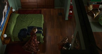 Movie still from “The Human Voice” (2020), directed by Pedro Almodóvar – A woman standing in front of a bed in a room; Wide shot, Overhead angle
