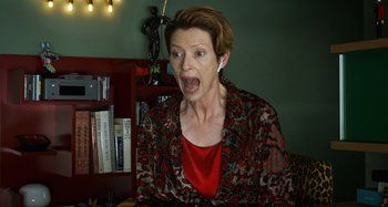 Movie still from “The Human Voice” (2020), directed by Pedro Almodóvar – A woman with short red hair and a red shirt is screaming; Medium shot, Low angle