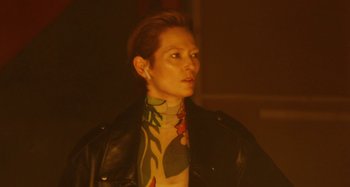 Movie still from “The Human Voice” (2020), directed by Pedro Almodóvar – A woman in a black leather jacket and a neck tie; Close Up shot, Over the shoulder angle