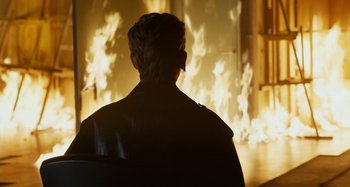 Movie still from “The Human Voice” (2020), directed by Pedro Almodóvar – A man in a leather jacket is in front of a fire; Medium shot, Over the shoulder angle