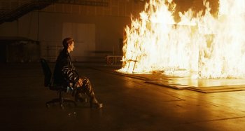 Movie still from “The Human Voice” (2020), directed by Pedro Almodóvar – A man sitting in front of a fire pit at night; Wide shot, High angle